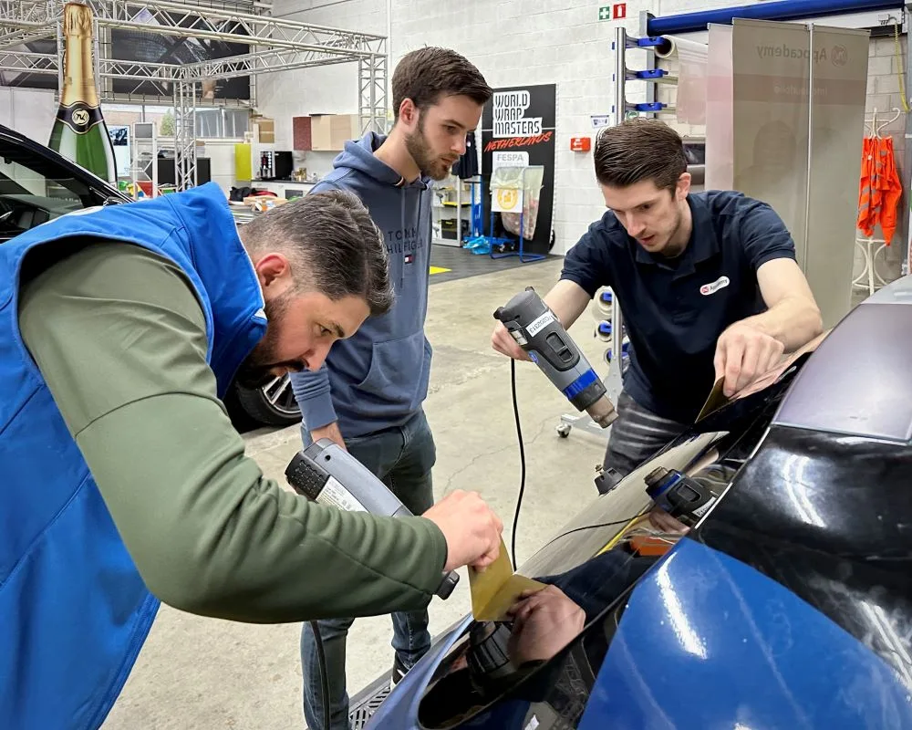 Trainer demonstreert raamfolie plakken bij oefenende cursisten tijdens Appcademy Automotive Windowfilm cursus