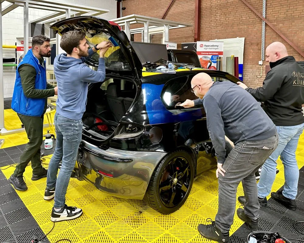 Praktijkoefeningen met cursisten die raamfolie aanbrengen op achterruit en zijruiten tijdens Appcademy Automotive Windowfilm workshop