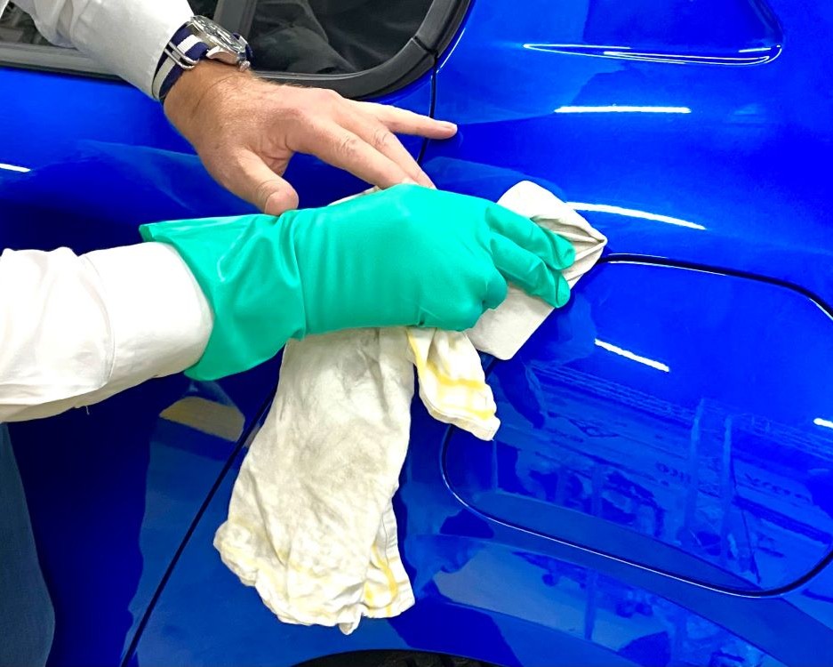 Trainer demonstreert hoe je een ondergrond reinigt en ontvet voordat zelfklevende folie wordt geplakt tijdens de Appcademy signmaker cursus