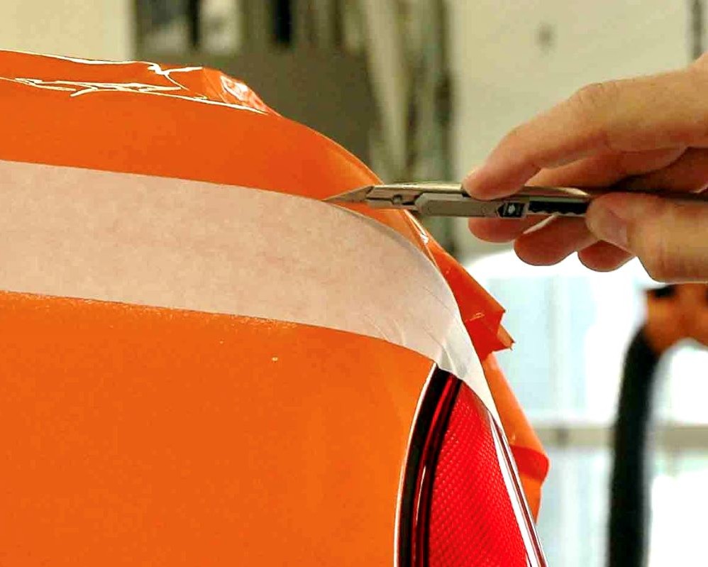 Cursist snijdt folie uit de hand af op een carrosserie langs een hulplijn tijdens de Appcademy signmaker advanced workshop