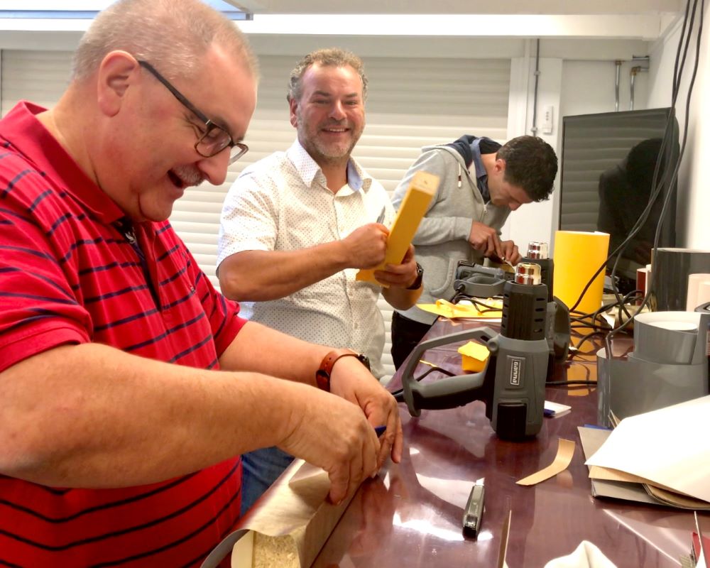 Cursisten wrappen tafelpoten als praktijkoefening tijdens de Appcademy training interieurfolie appliceren en keukens beplakken