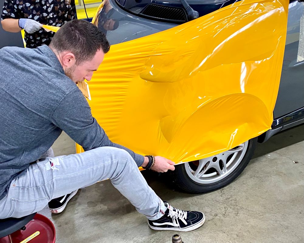 Cursist carwrapt voorscherm spatbord auto als praktijkoefening tijdens Appcademy carwrap workshop