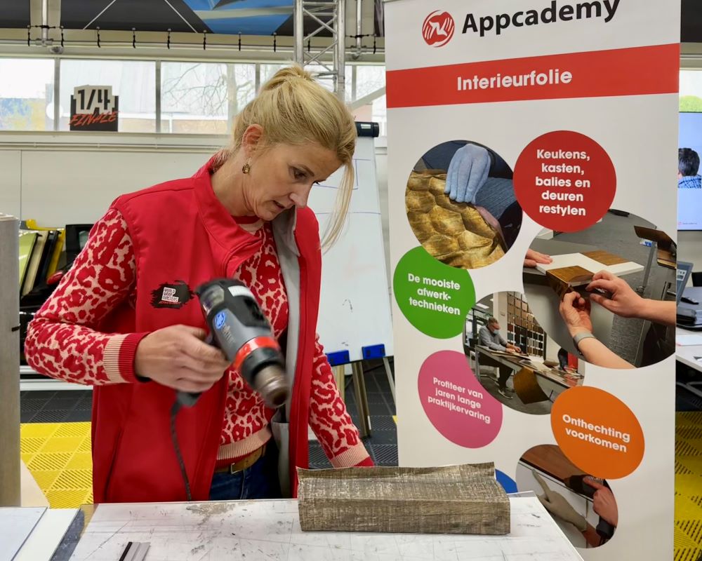 Cursist wrapt met interieurfolie op een keuken paneel als praktijkoefening tijdens de Appcademy training kitchen wrap