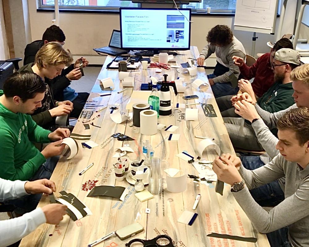 Groep studenten zit aan tafel terwijl ze snij oefeningen doen tijdens Appcademy workshop en gastcollege op ROC / MBO opleiding signmaker