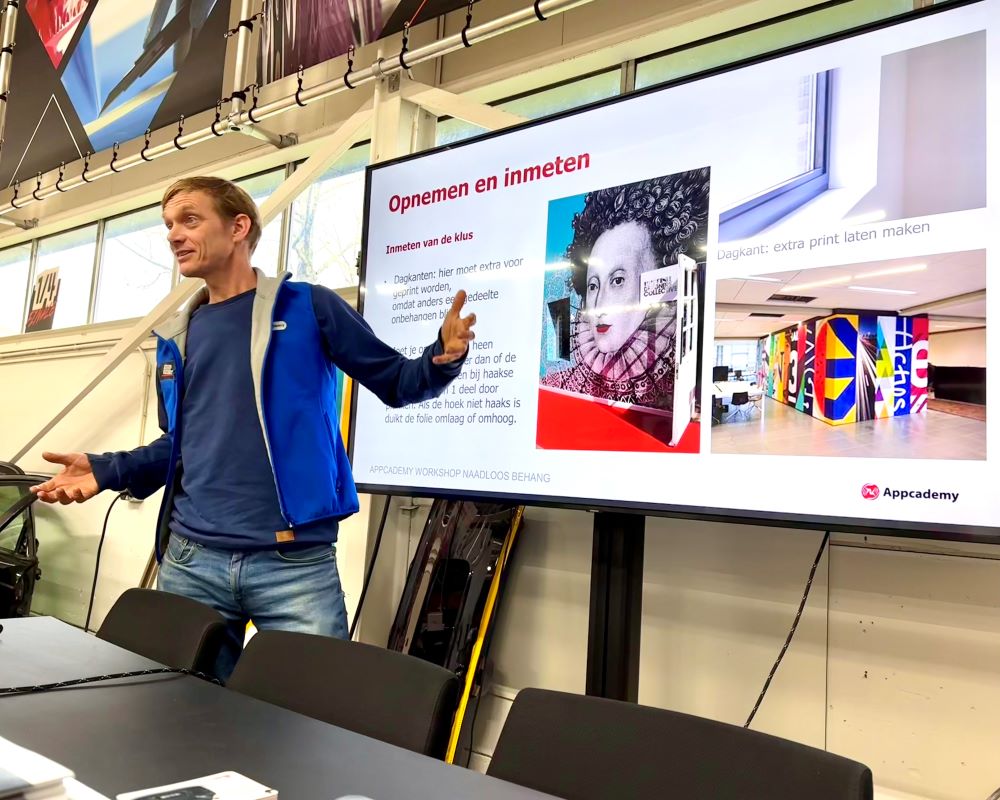 Trainer gebruikt power point via LCD scherm tijdens Appcademy Naadloos fotobehang training