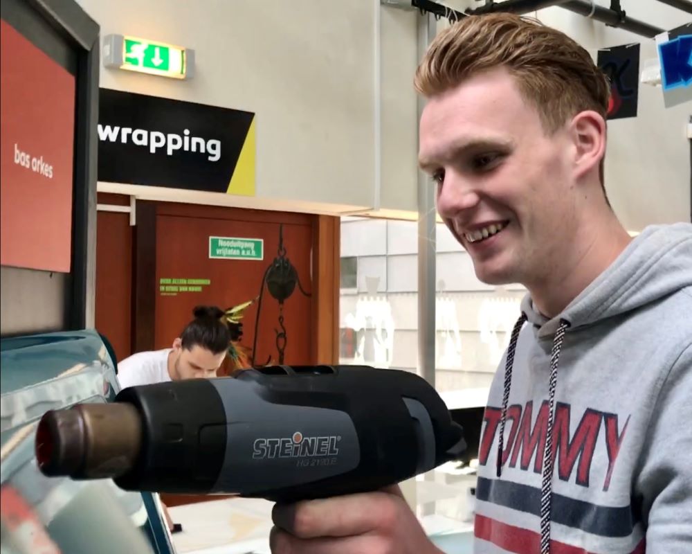 Student doet praktijkoefening folie verwarmen met een föhn tijdens Appcademy workshop en gastcollege op ROC / MBO opleiding signmaker