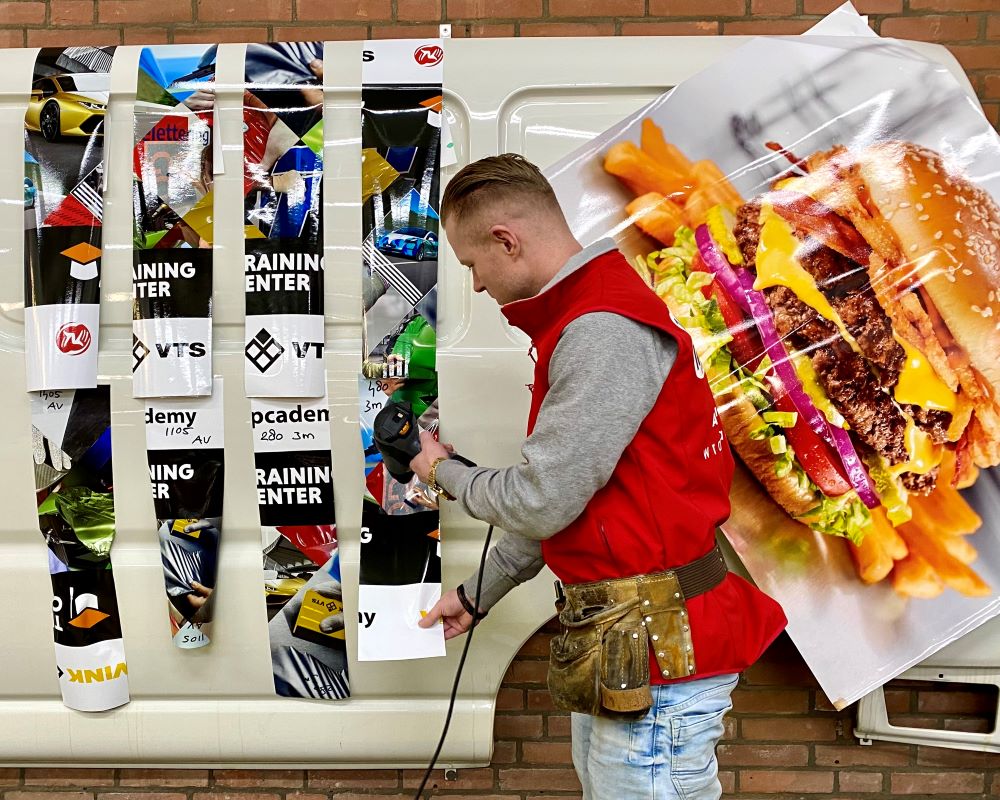 Trainer demonstreert welke verschillen in printfolie eigenschappen een rol spelen bij vervorming in een profielen tijdens de Appcademy signmaker advanced training