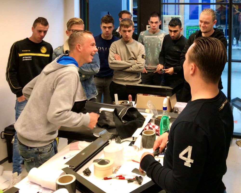 Studenten hebben pret bij beplakken kozijnen tijdens Appcademy workshop en gastcollege op ROC / MBO opleiding schilderen