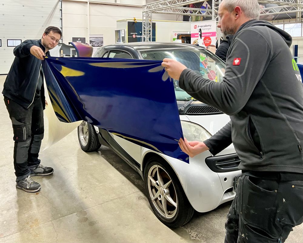 Cursisten carwrappen zijkant auto als praktijkoefening tijdens Appcademy carwrap training