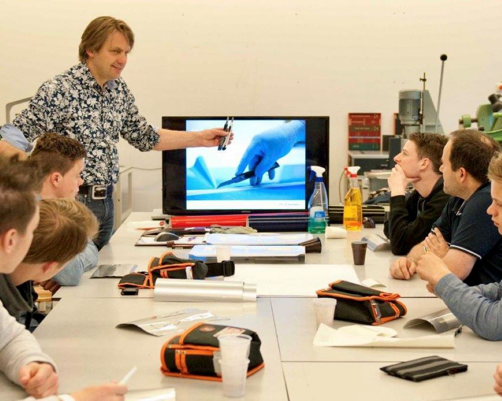 Trainer gastdocent staat voor de klas bij power point presentatie tijdens Appcademy workshop en gastcollege op ROC / MBO signopleiding