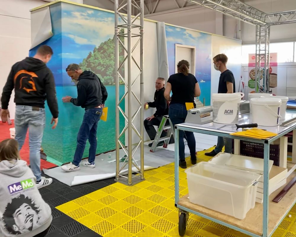 Cursisten plakken veel meters groot formaat naadloos fotobehang op wanden tijdens Appcademy Naadloos fotobehang workshop