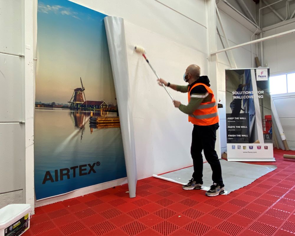 Cursist smeert behanglijm van Flexx of Vescom op wand tijdens Appcademy Naadloos fotobehang cursus