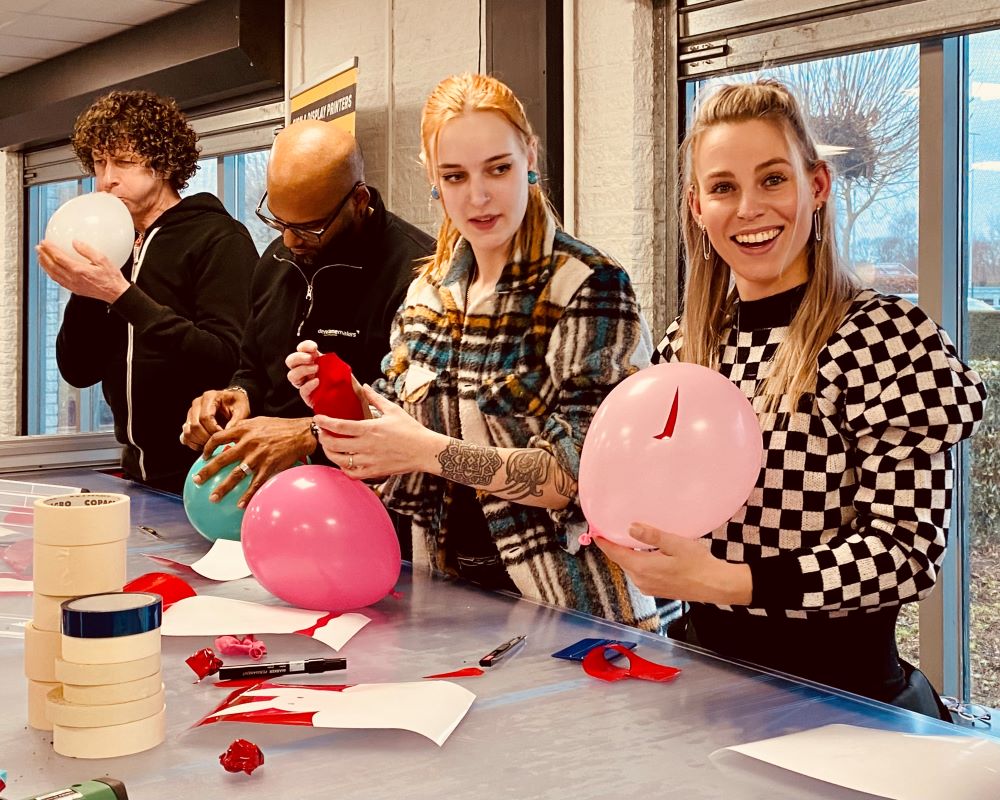 Cursisten snijden wrapfolie af op ballonnen als praktijkoefening tijdens Appcademy wrap cursus
