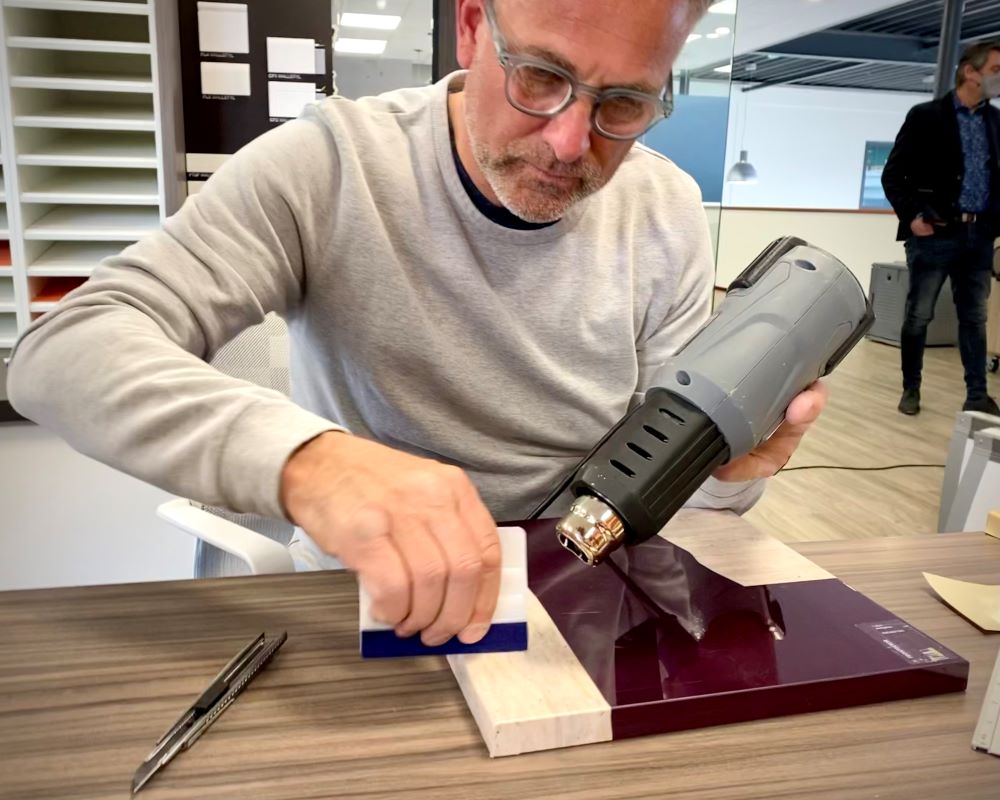 Cursist werkt interieurfolie technisch juist af op een keukenkast frontje of ladefront als praktijkoefening tijdens de Appcademy training keukens wrappen