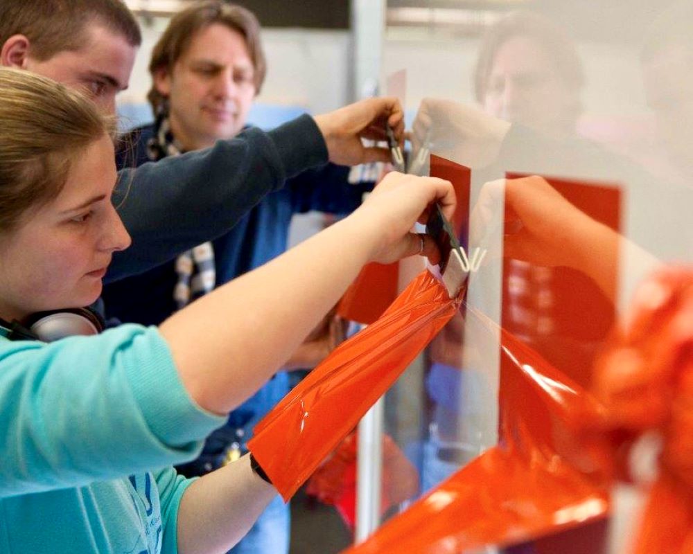 Studenten middelbaar beroepsonderwijs doen praktijkoefeningen onder toeziend oog van trainer tijdens Appcademy workshop en gastcollege op ROC / MBO opleiding signmaker