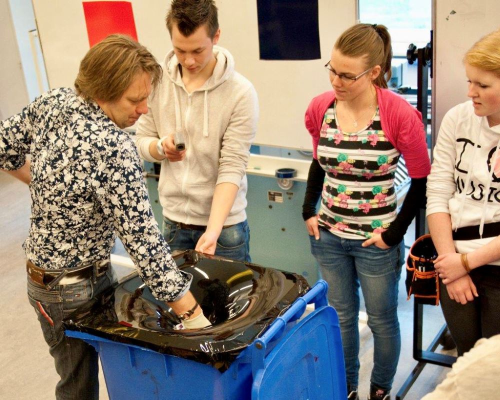 Trainer geeft demonstratie folie uitrekken aan studenten middelbaar beroepsonderwijs tijdens Appcademy workshop en gastcollege op ROC / MBO opleiding signmaker