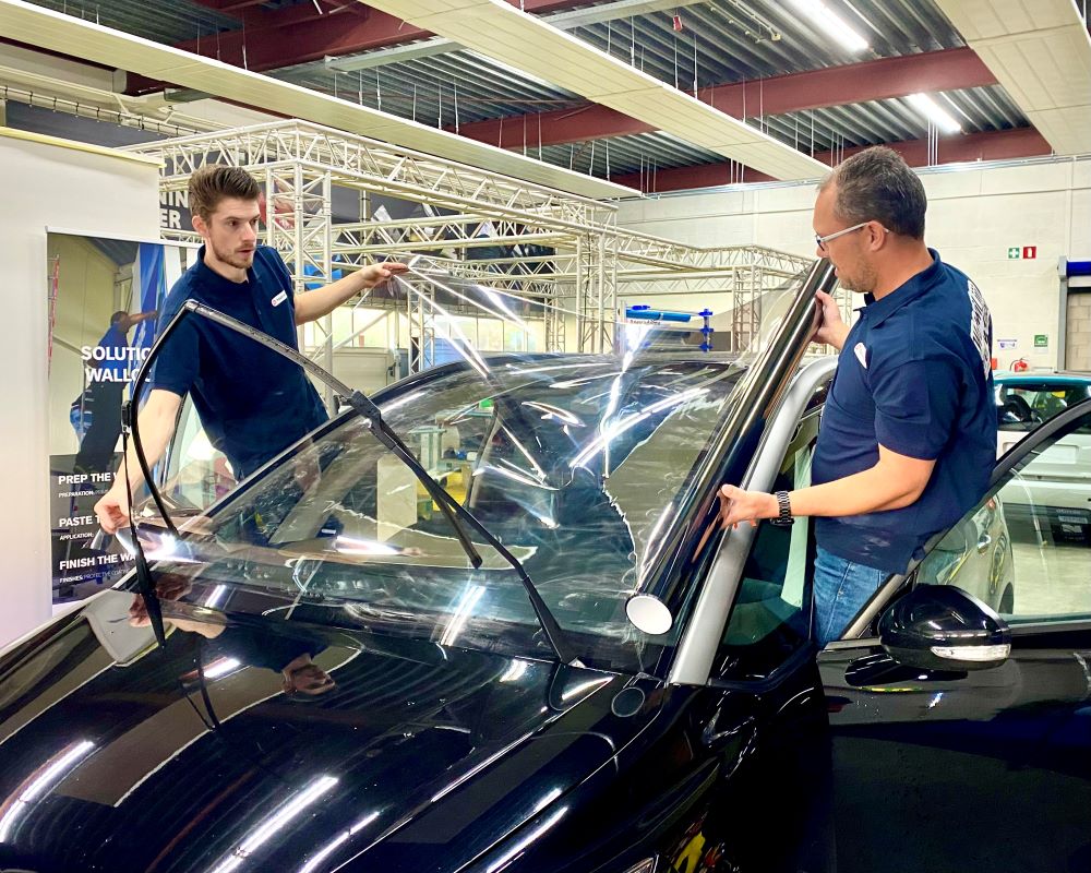 2 Trainers demonstreren plakken van raamfolie op bolle ruit tijdens Appcademy Automotive Windowfilm opeiding