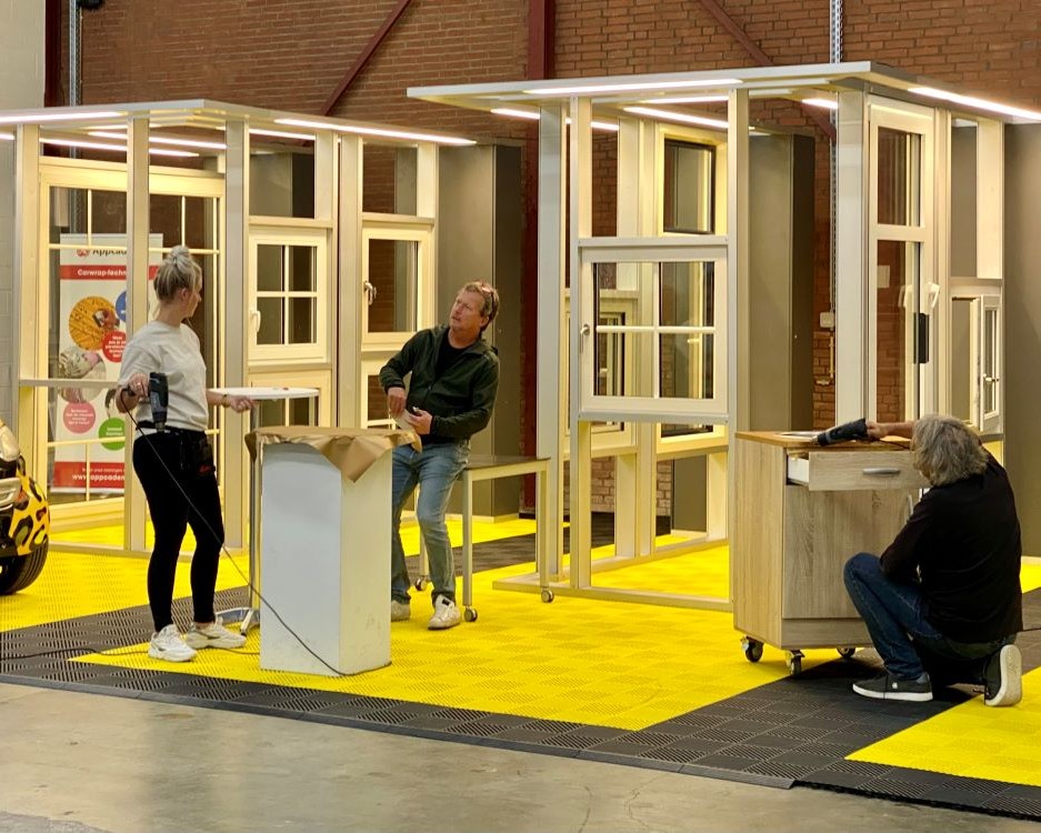 Cursisten beplakken een balie als praktijkoefening tijdens de Appcademy training interieurfolie en keukens wrappen