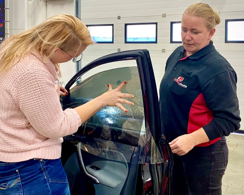 Cursist doet praktijkoefening raamfolie aanbrengen op zijruit met draairamen tijdens Appcademy Automotive Windowfilm cursus