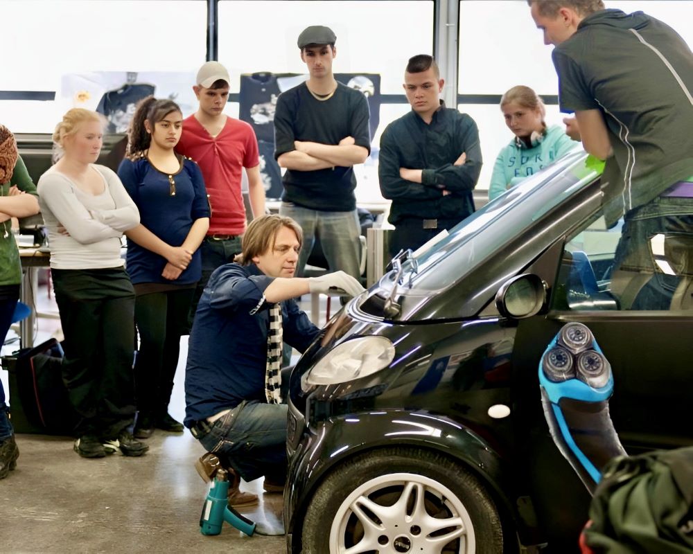 Trainer geeft demonstratie folie wrappen en plakken aan groep studenten tijdens Appcademy workshop en gastcollege op ROC / MBO signopleiding