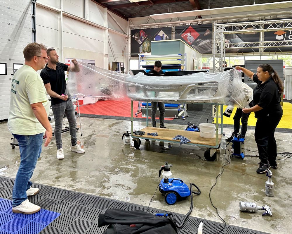 Cursisten leggen PPF uit bulk aan op bumper tijdens Appcademy Paint Protection Film cursus