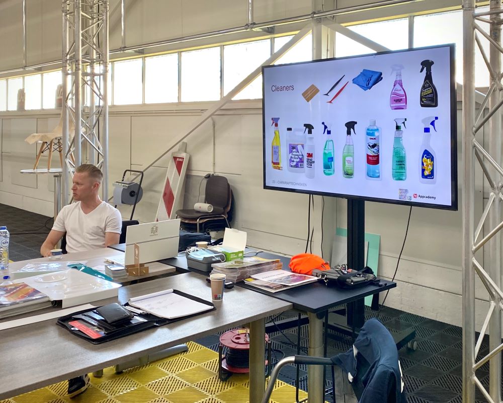 Trainer verteld cursisten mbv een power point welke reinigingsmiddelen voor ondergronden geadviseerd worden tijdens de Appcademy opleiding signmaker advanced